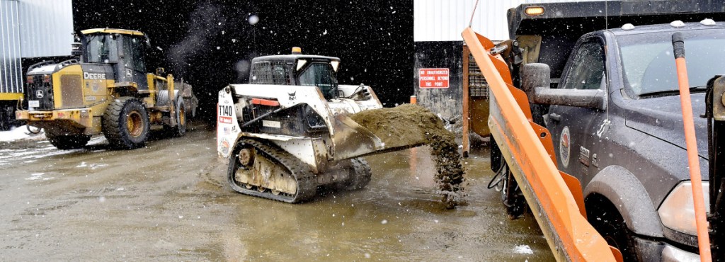 Larry Colsen fills a Waterville Public Works plow truck with sand as Mike Folsom uses a bucket loader to fill another truck Tuesday at the department in anticipation of Wednesday's snowstorm.