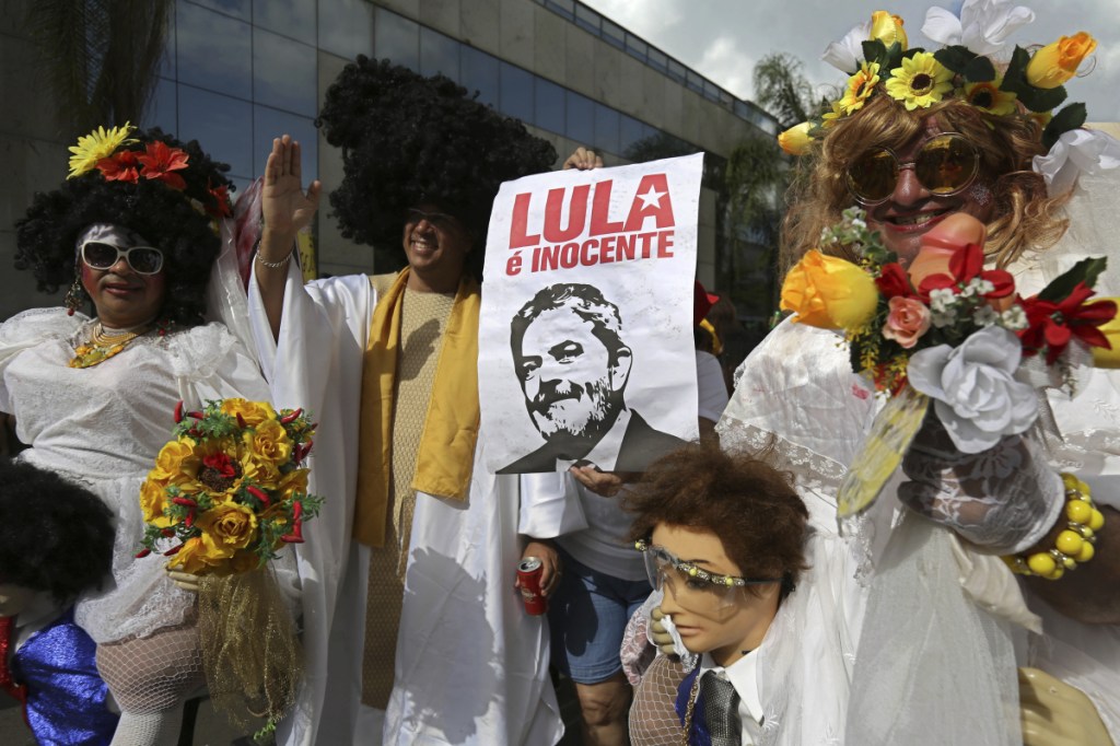 Revelers in white costumes carry an image of Brazil's former President Luiz Ignacio Lula da Silva below the Portuguese phrase "Lula the Innocent" during the Pacotao street carnival party in Brasilia, Brazil, Sunday. Lula faces a growing risk of being arrested within weeks after a corruption conviction.