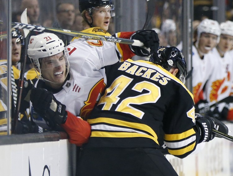 Boston's David Backes checks Calgary's Garnet Hathaway in the first period Tuesday night in Boston. Backes had two assists as the Bruins topped the Flames 5-2 in their last home game until Feb. 27.