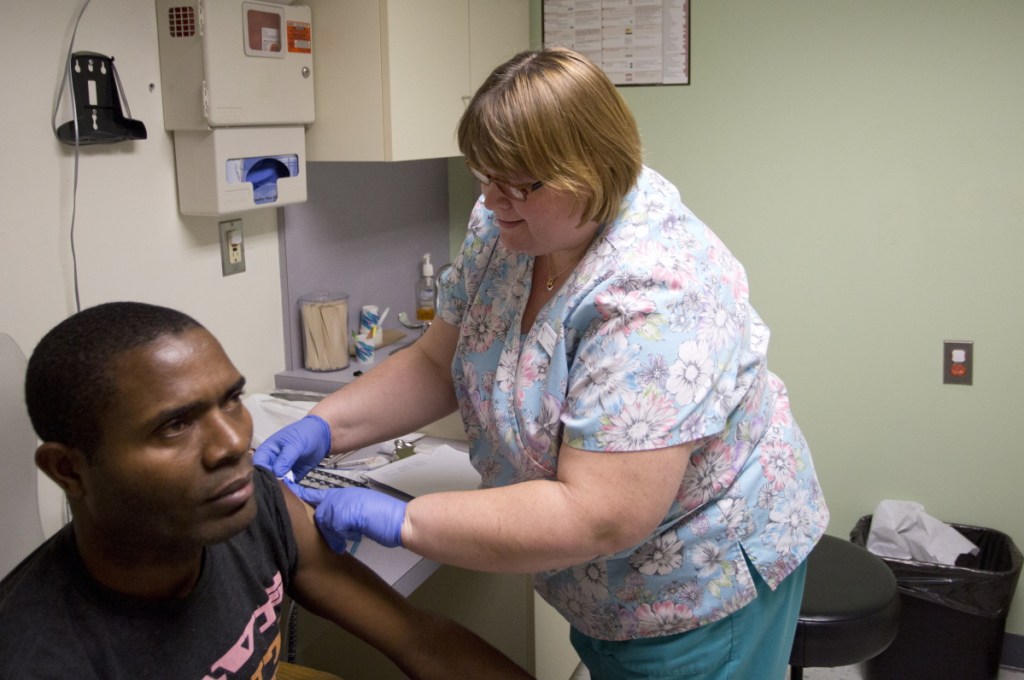Susan Huff administers a flu vaccine to Bruno Mbango Enyaka at the Portland Community Health Center in 2015.