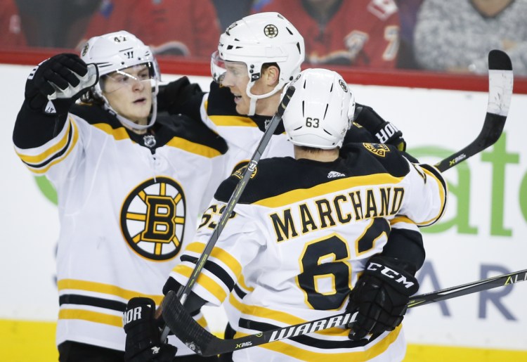 Boston's Brad Marchand, right, celebrates his winning goal in overtime Monday at Calgary.