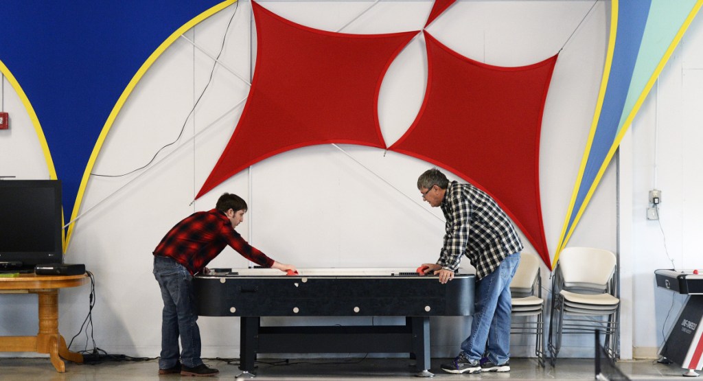 David Conrad, right, of PSL Services/STRIVE plays air hockey with Brendan Young, who has intellectual disabilities, as part of a program at STRIVE. Young's mother said that when the group home her son stays at in Windham has a run of stable, quality employees, he thrives.