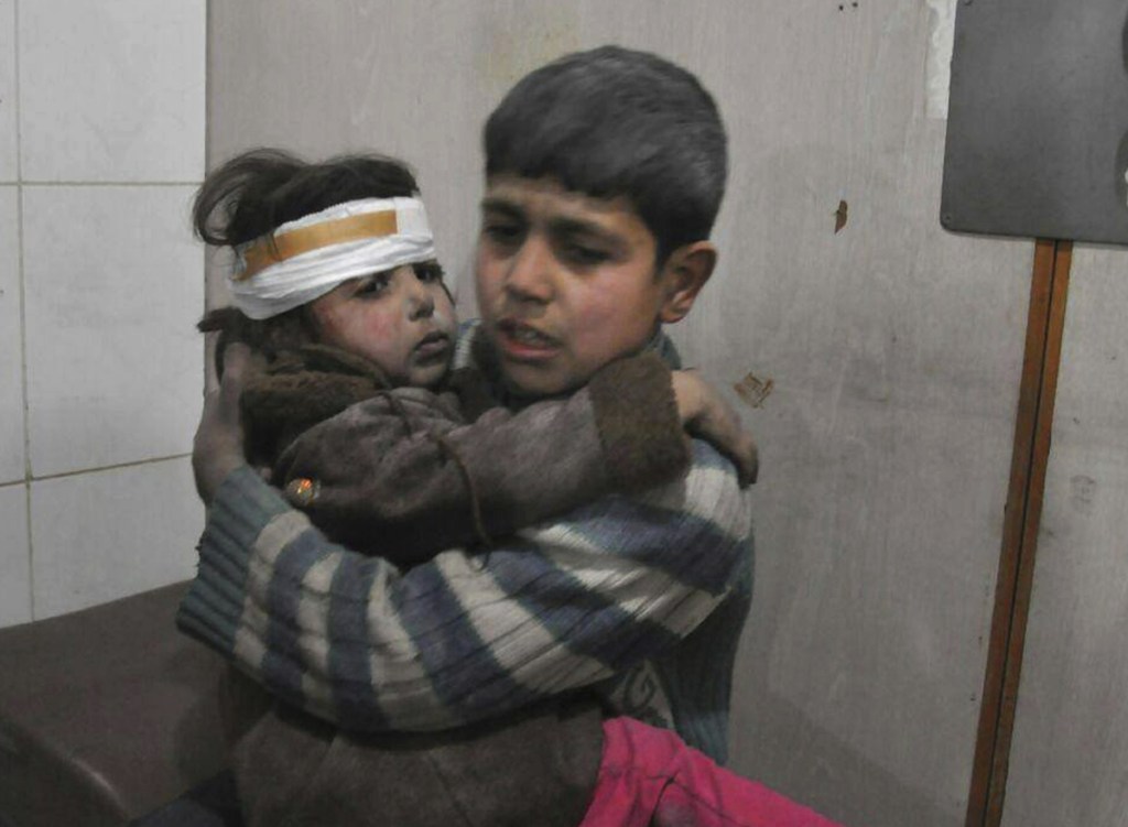 Two Syrian children who were wounded during airstrikes sit in a makeshift hospital in Ghouta on Feb. 21.