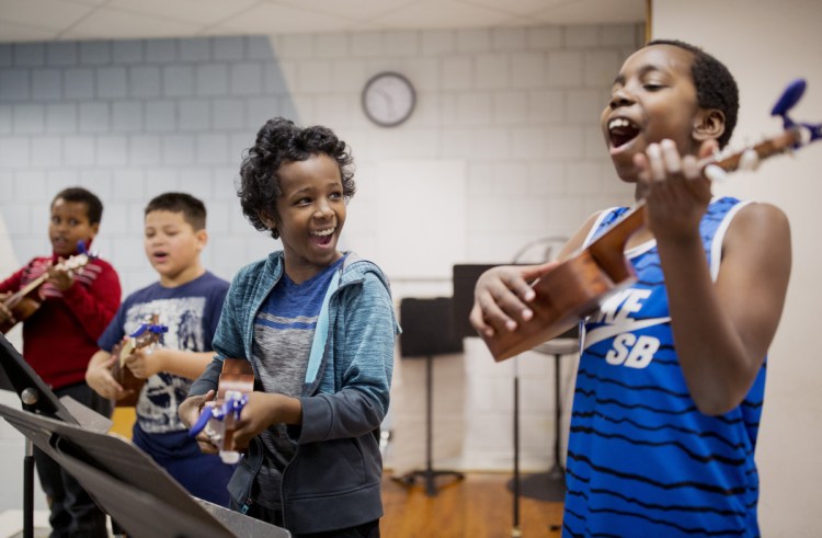 Khalid Mahmed, 11,  and John Cubahiro, 9, center, practice before their concert. "It's a very social, smile-inducing instrument," says camp director Lee Urban, owner of nearly 50 ukuleles.