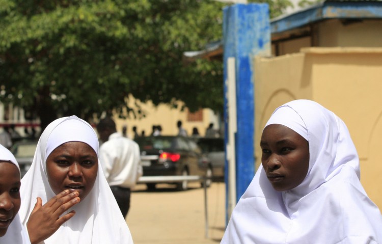 Young women stand in front of a school in Maiduguri, Nigeria.  Militants kidnapped 276 girls in 2014 from a boarding school. About 100 of those girls have never returned.