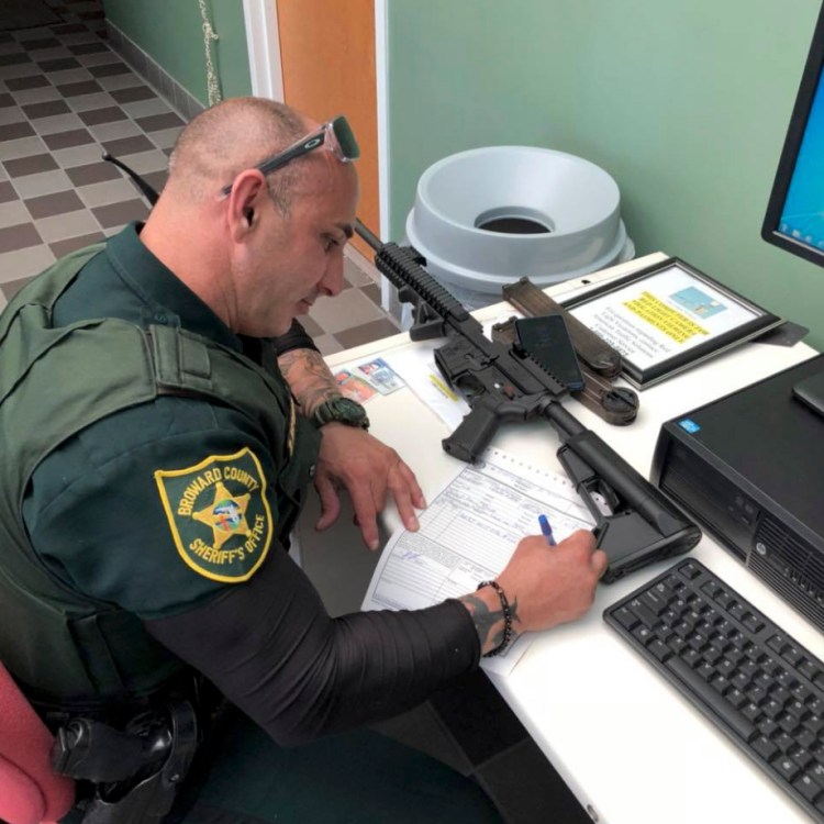A Broward County Florida Sheriff's Deputy processes paperwork to take possession of and destroy an AR-style firearm owned by Ben Dickmann, a photographer in Florida. Dickmann turned in his weapon after the shooting at Marjory Stoneman Douglas High School in Parkland, Fla., that left 17 students and adults killed. In the days since a 19-year-old man at a Florida high school used an AR-15 to kill 17 former classmates, it has fueled a newly enraged public over the proliferation of guns in America. The No. 1 target is the AR-15, banned for a decade until 2004 but with millions sold since they were allowed back on the market.