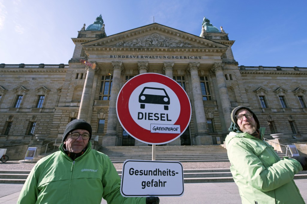 Environment activists stand in front of the Federal Administrative Court prior to a trial in Leipzig, Germany, Tuesday. The German court ruled Tuesday that cities can impose driving bans on diesel cars to combat air pollution, a decision that could affect millions of drivers and the country's powerful auto industry.
