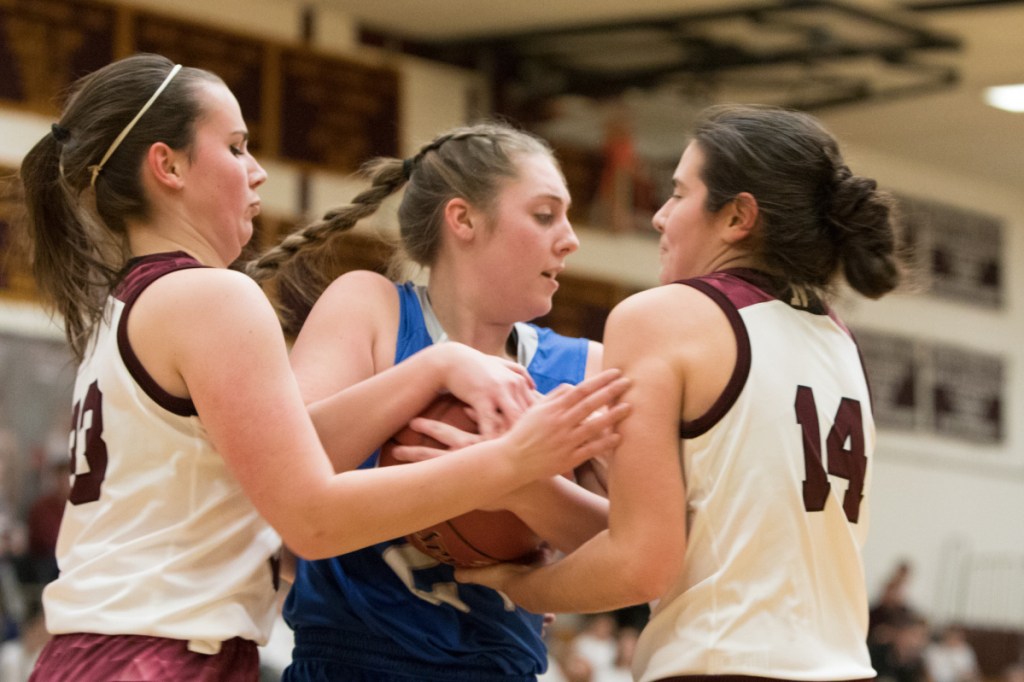Nokomis seniors Chelsea Crockett, right, and Aren Herrick try to rip the ball away from Lawrence's Molly Folsom during a Kennebec Valley Athletic Conference Class A game Tuesday night in Newport.