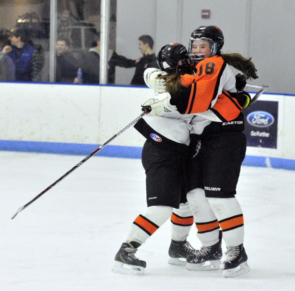 Winslow/Gardiner's Lindsey Bell, left, hugs teammate Bailey Robbins after Robbins scored a goal to against Brunswick during a North quarterfinal game Thursday at the Camden National Bank Ice Vault in Hallowell.
