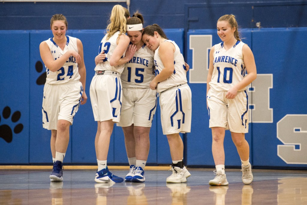Lawrence's Hunter Mercier (15) is comforted by teammates Kirsten Gordon (12) and Haley Holt, right center, after scoring the first two points of the game and exiting with an injury against Skowhegan on Thursday in Fairfield.