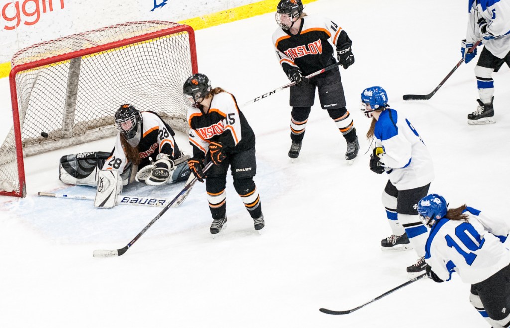 Lewiston/Monmouth/Oak Hill's Gemma Landry, bottom right, watches her shot sail past Winslow/Gardiner goalie Cassandra Demers during the second period of a playoff game Friday night at the Androscoggin Bank Colisee in Lewiston.