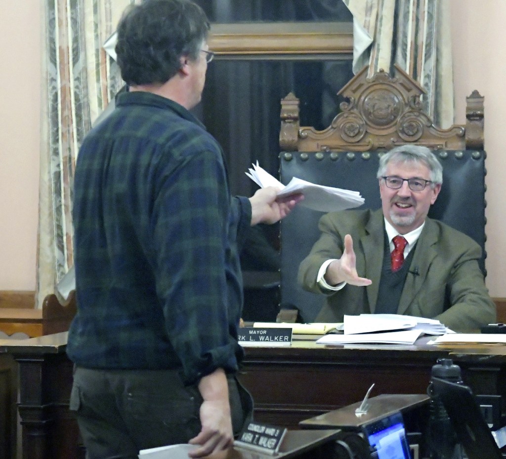 Geoff Houghton hands a petition to Hallowell Mayor Mark Walker on Monday urging the installation of a crosswalk in front of his Water Street business, The Liberal Cup, during a Hallowell City Council meeting. The council voted in favor of adding the feature to the U.S. Route 201 reconstruction project, which has been in planning for several years.