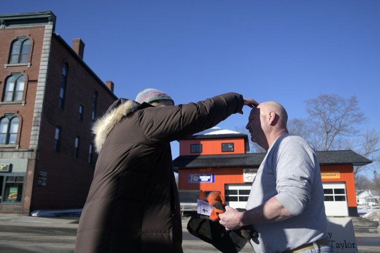 Rev. Susan Taylor, of St. Andrew's Episcopal Church, places ashes on the head of Steve Kennedy in downtown Winthrop on Wednesday.