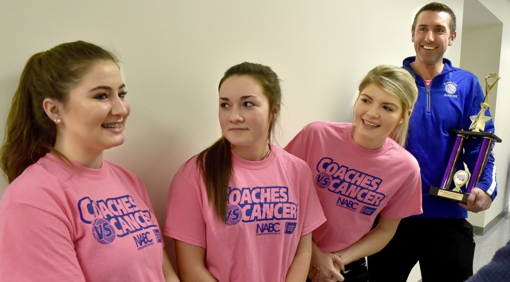 Erskine Academy girls basketball players Lydia Boucher, left, Lauren Wood, middle, Bailey Cloutier and coach Mitch Donar, right, speak about the team and community efforts in raising $10,000 for the American Cancer Society during a ceremony Tuesday at the South China school.
