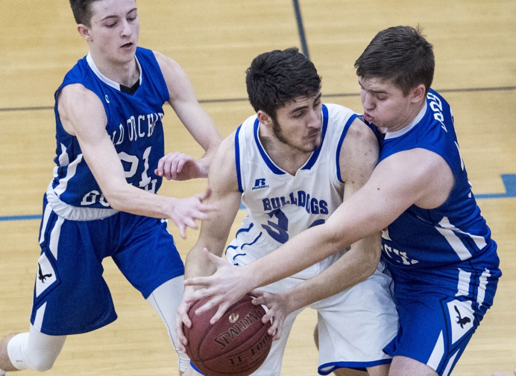 Madison's Jacob Meader, center, looks to pass the ball as he is defended by Old Orchard Beach's Kyle Allen, right, and Ryun Hogan, left, in a Class C South preliminary game Wednesday in Madison.