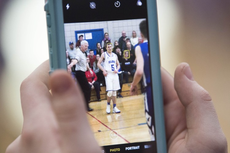 A Madison Area Memorial High School students snaps a photo Tuesday of Sean Whalen (5) in the Class C boys preliminary game against Old Orchard Beach High School in Madison.