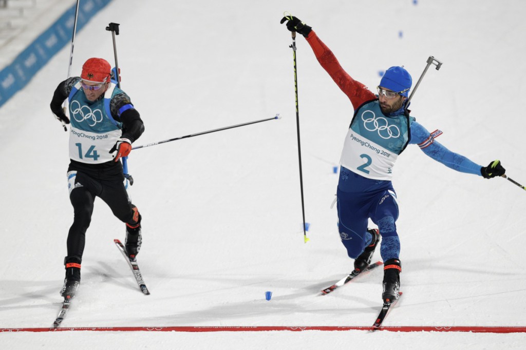 Simon Schempp, of Germany, left, and Martin Fourcade, of France, right, race across the finish line during the men's 15-kilometer mass start biathlon Sunday at the 2018 Winter Olympics in Pyeongchang, South Korea.