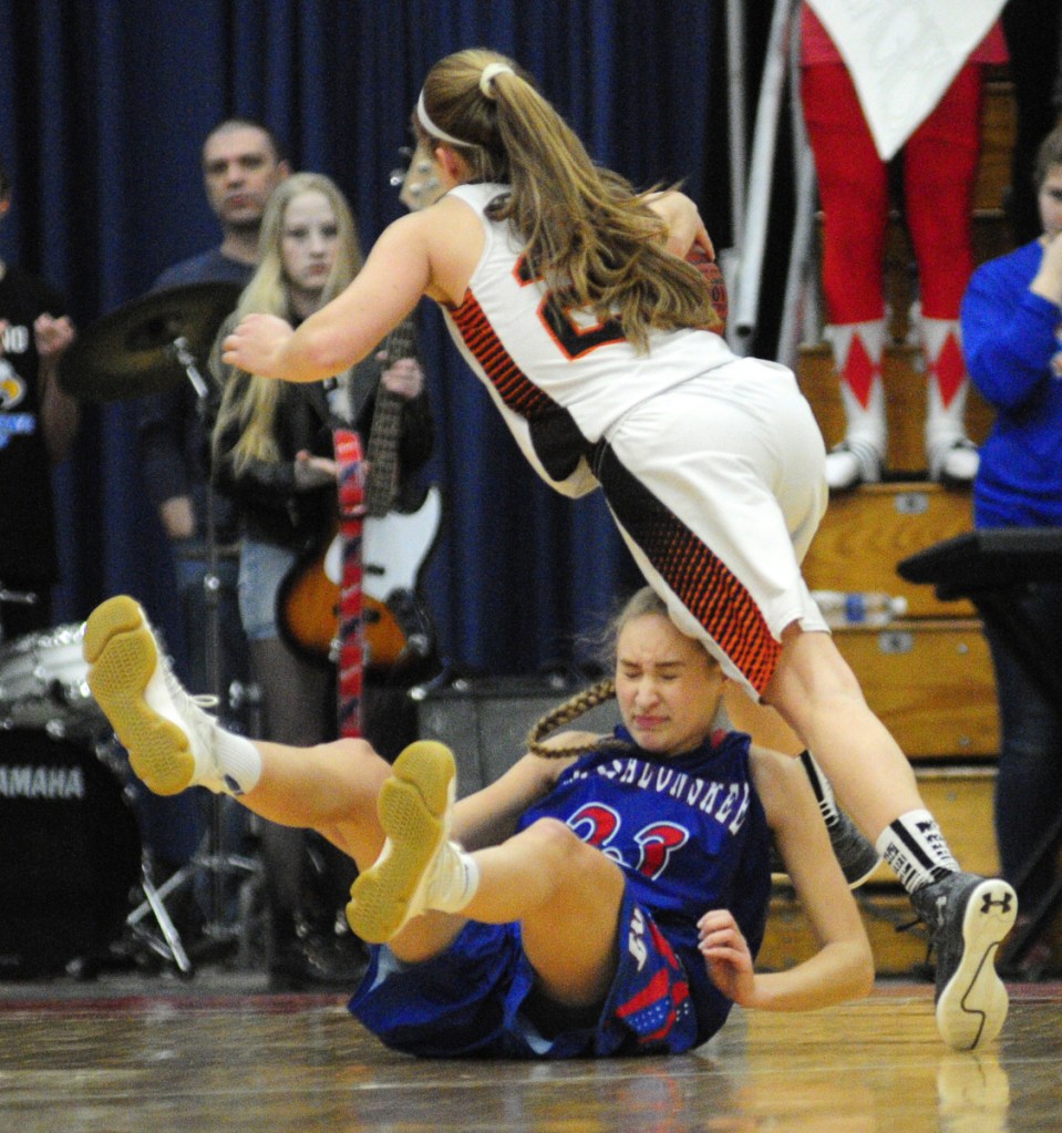 Skowhegan junior guard Sydney Ames, top, runs over Messalonskee senior guard/forward Ally Turner during a Class A North semifinal game Wednesday at the Augusta Civic Center.