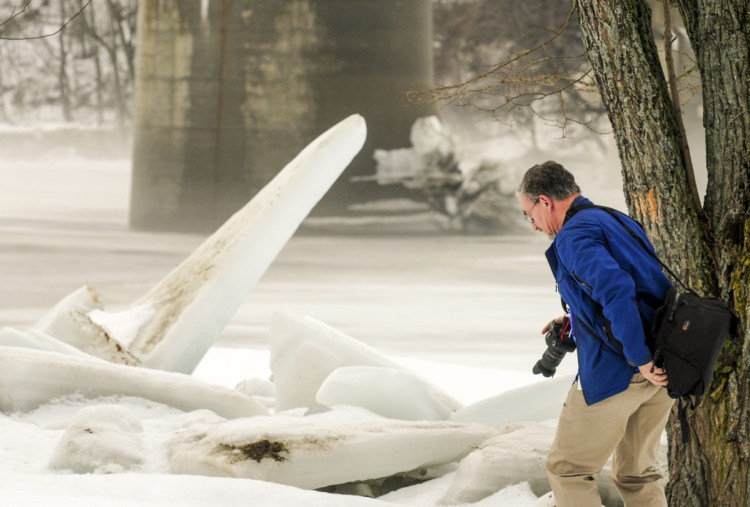 Tim True, of Chelsea, moves to get a better angle for photographing ice slabs Wednesday at the East Side Boat Launch in Augusta. Large chunks of ice lined both sides of the Kennebec River from last month's ice jam flooding.