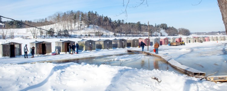 People walk across a bridge and onto the frozen Kennebec River on Dec. 30, 2017, at Baker Brothers Smelt Camps in Pittston. Baker's is putting its camps away Sunday, three days ahead of an expected arrival of U.S. Coast Guard icebreakers.