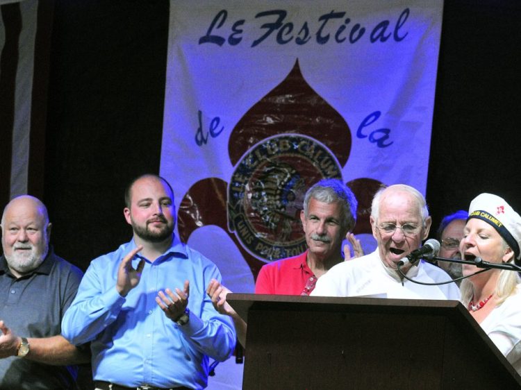 Larry Guimond and Rachel Boucher Ellis lead Le Club Calumet anthem during the opening night of Le Festival de La Bastille on July 8, 2016, in Augusta, as others — including state Sen. Roger Katz, R-Augusta, back center, look on. Katz sponsored legislation, endorsed by a legislative committee on Monday, that removes a $1,000 cap on the amount of money nonprofit groups such as Le Club Calumet can offer as a cash prize in their fundraising raffles.