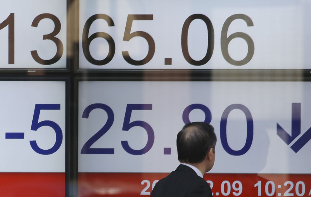 A man looks at numbers showing the downturn Friday on an electronic stock board at a securities firm in Tokyo.