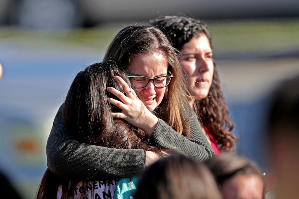 Students released from a lockdown embrace following Wednesday's shooting. Police identified the gunman as a former student.