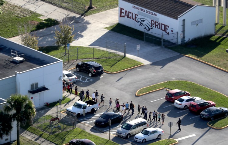 Students are evacuated by police from Marjorie Stoneman Douglas High School in Parkland, Fla., on Wednesday, Feb. 14, 2018, after a shooter opened fire on the campus. 
