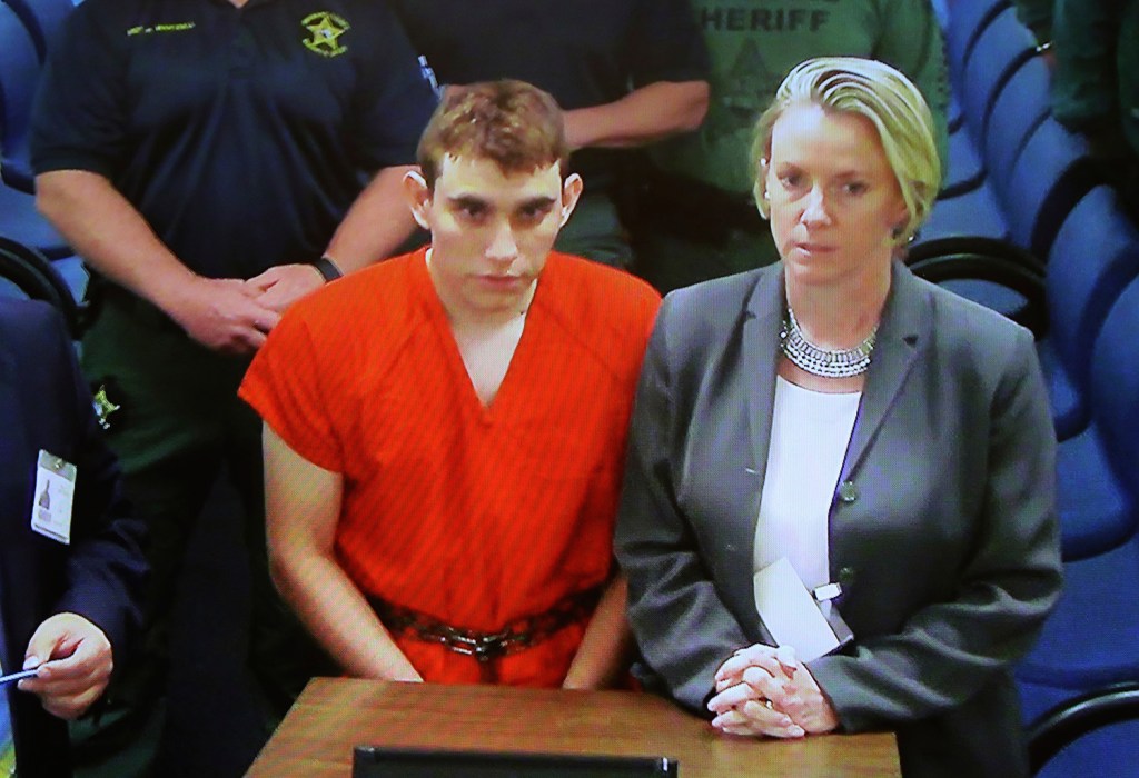 A video monitor shows school shooting suspect Nikolas Cruz, left, making an appearance in Broward County Court in Fort Lauderdale, Florida. Cruz is accused of opening fire at a high school in Parkland, killing least 17 people.