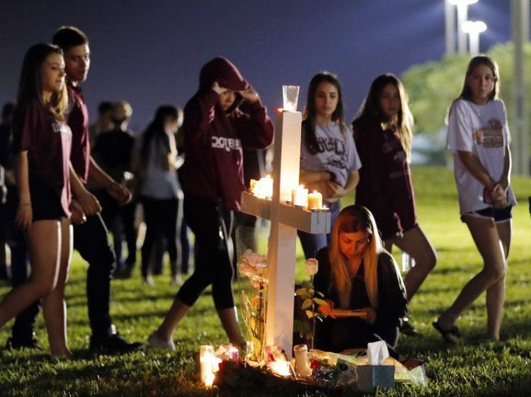 Students walk past one of seventeen crosses after a candlelight vigil for the victims of the Wednesday shooting at Marjory Stoneman Douglas High School, in Parkland, Fla., Thursday.
