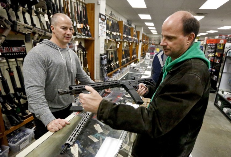 Wes Morosky, left, owner of Duke's Sport Shop in New Castle, Pa., helps Ron Detka as he shops for a rifle Friday. Morosky said business has gone up recently, but that's thanks to the annual infusion of tax refund checks. 