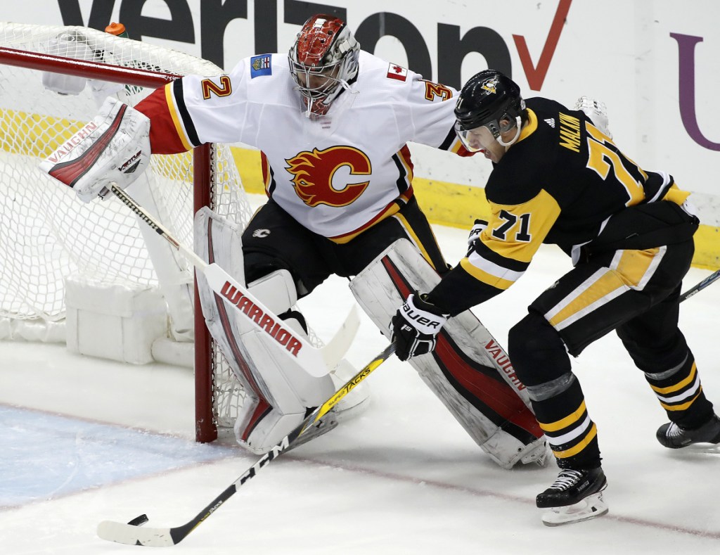 Evgeni Malkin gathers the puck and prepares to put it behind Calgary goaltender Jon Gillies, of South Portland, in the first period Monday night in Pittsburgh. The Penguins won in OT.