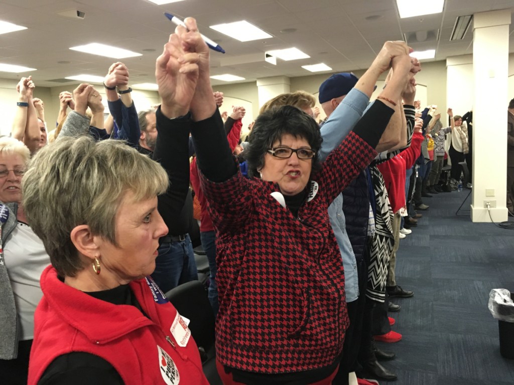 Retired teacher Meg Judd raises her arms and chants "Find funding first!" during a legislative committee hearing in Frankfort, Ky.,  on Wednesday. Lawmakers voted to advance a bill that would reduce annual cost-of-living benefits for retired teachers to 1 percent from 1.5 percent.