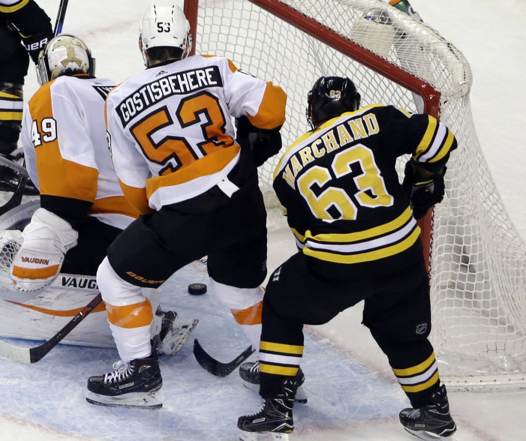 Brad Marchand reaches behind Flyers goalie Alex Lyon and Shayne Gostisbehere for the winning goal in Boston's 3-2 victory.