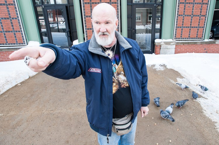 David Sites points to Oak Park Apartments in Lewiston, where he lives, as birds feed on bread he has just thrown down for them. Despite a threat of eviction for feeding the birds, Sites plans to continue feeding the pigeons, as he has done for the past 10 years. Visit sunjournal.com to watch a video of Sites feeding the birds and explaining why he plans to continue. 