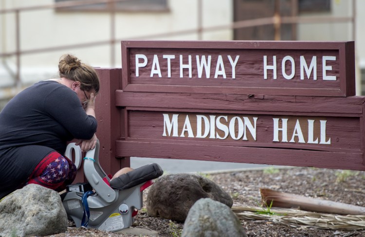 A woman who declined to give her name cries after placing flowers at a sign at the Veterans Home of California the morning after a gunman killed three hostages and himself there, in Yountville, Calif., on Saturday.