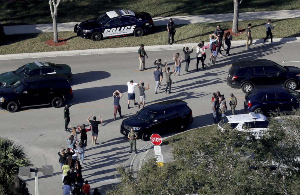 Students hold their hands in the air as they are evacuated by police from Marjory Stoneman Douglas High School in Parkland, Fla., after a shooter opened fire on the campus. Prosecutors announced they will seek the death penalty in the case.