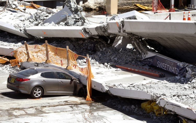 Cars are shown crushed under a section of a collapsed pedestrian bridge Friday.