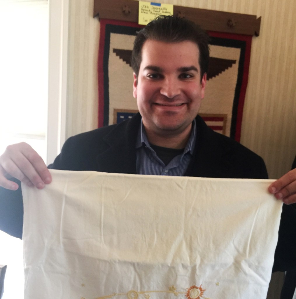 Adam Sackowitz displays an embroidered pillowcase with celestial bodies on it that belonged to the late senator and astronaut John Glenn.