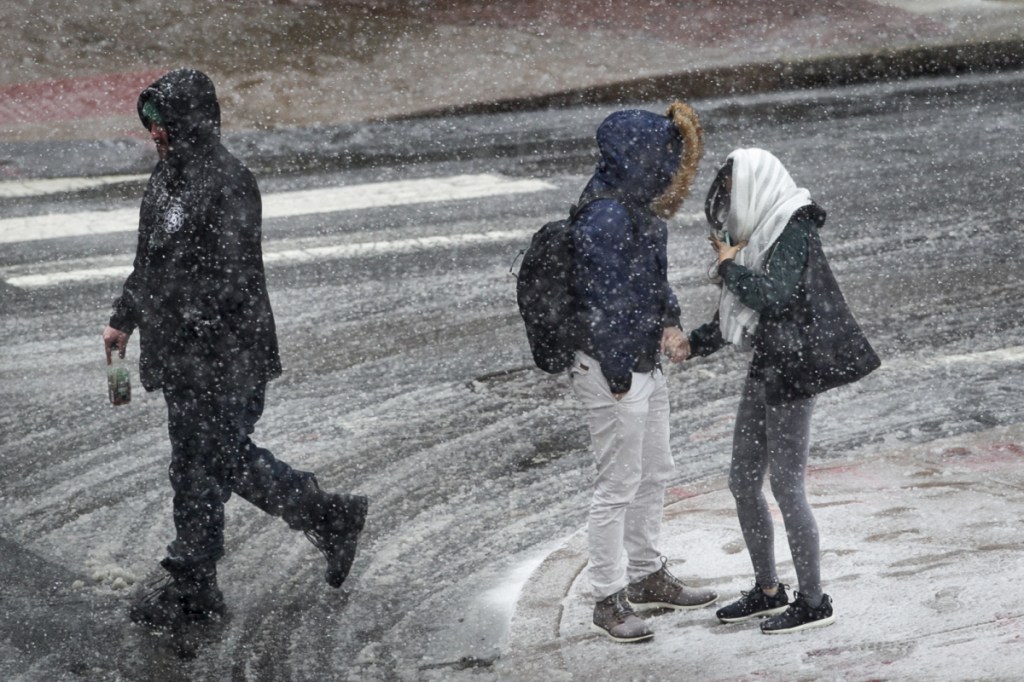 People hold hands and huddle together as snow falls in Philadelphia on Wednesday.