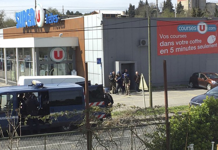 Police gather outside a supermarket in Trebes, southern France, Friday March 23, 2018. An armed man took hostages in a supermarket in southern France on Friday, killing two and injuring about a dozen others, police said. He had earlier opened fire on officers nearby.(Newsflare/Tarbouriech Roseline via AP)