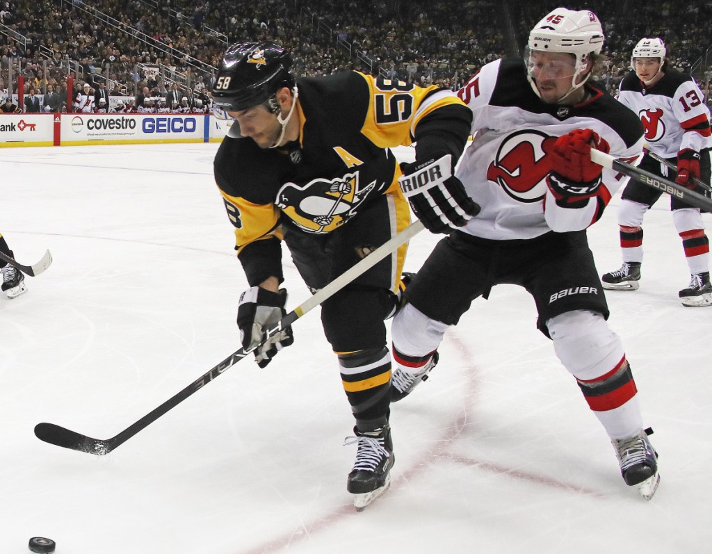 Kris Letang of the Pittsburgh Penguins skates past Sami Vatanen of the New Jersey Devils during the second period of New Jersey's 4-3 overtime victory on the road Friday night.