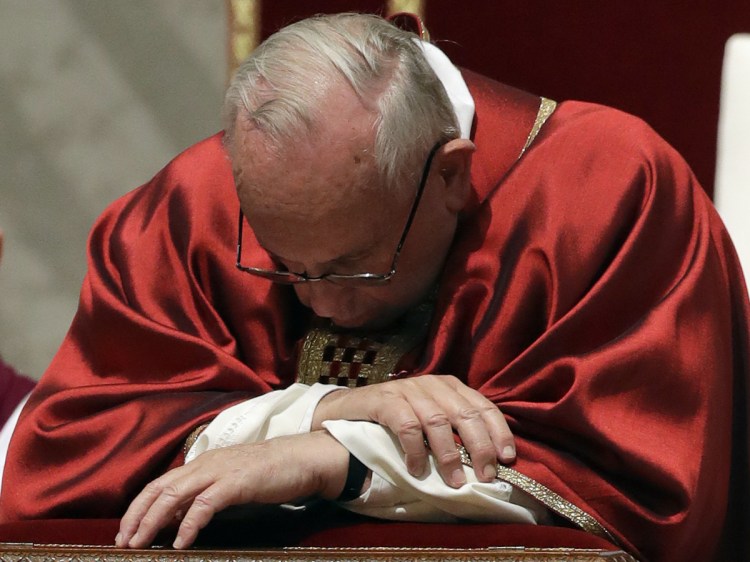 Pope Francis kneels as he celebrates the Good Friday Passion of Christ Mass inside St. Peter's Basilica, at the Vatican on Friday.