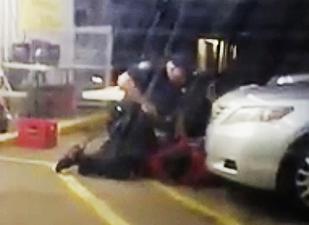 In this image made from video provided by Arthur Reed, Alton Sterling is restrained by two police officers outside a convenience store in Baton Rouge, La., on July 5, 2016. Moments later, one of the officers shot and killed Sterling.