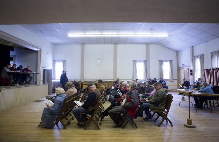 Cornville residents raise their hands to vote on a motion Saturday during Town Meeting at the Cornville Town Hall.