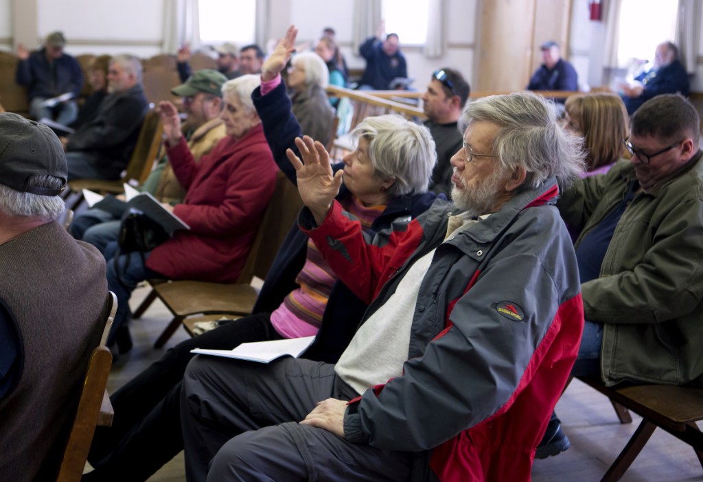 Anna Court, left, and Jonathan Goldthwaite raise their hands to vote for a motion Saturday during Town Meeting at the Cornville Town Hall.