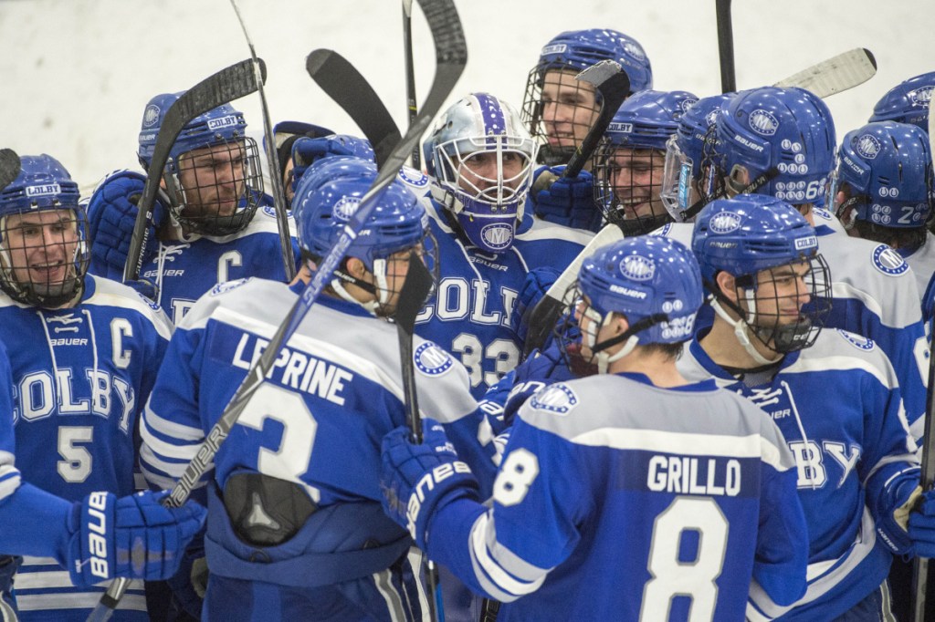 The Colby College hockey team swarms goaltender Sean Lawrence following a 4-2 win over the University of New England in the NCAA Division III hockey tournament Saturday night in Biddeford. 