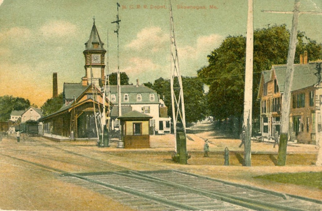 The Kennebec Valley Inn, originally the Maine Central Railroad Hotel, stands in the background of the train station with a clock tower, about 1905, in downtown Skowhegan.
