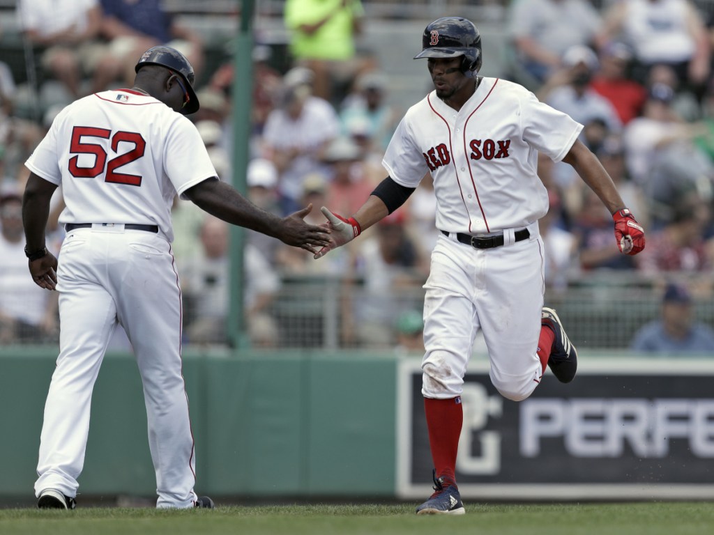 Boston Red Sox shortstop Xander Bogaerts celebrates his home run off Phillies pitcher Drew Hutchison with third base coach Carlos Febles (52) during the fourth inning Monday.