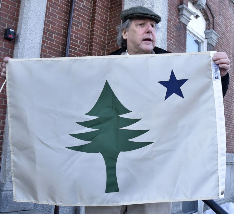 Somerset County Commissioner Robert Sezak holds a replica of the original state of Maine flag used from 1901 through 1909 before the flag was hoisted up a flagpole at the Somerset Superior Courthouse in Skowhegan on Wednesday.